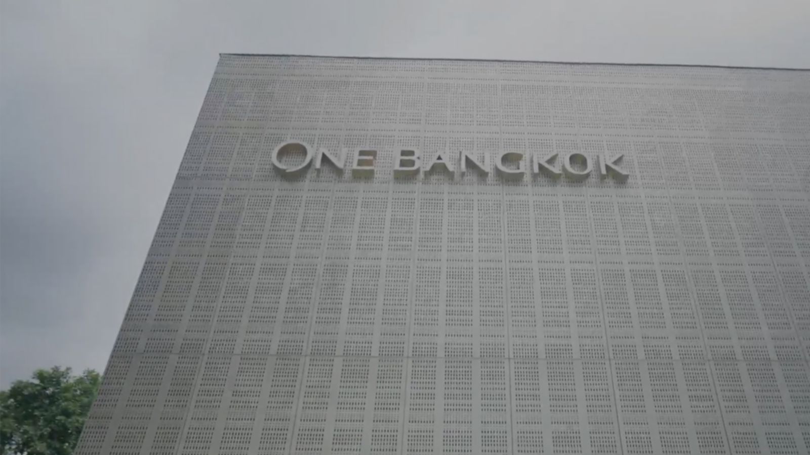 Exterior view of building with perforated facade panels and large text reading One Bangkok on the wall.