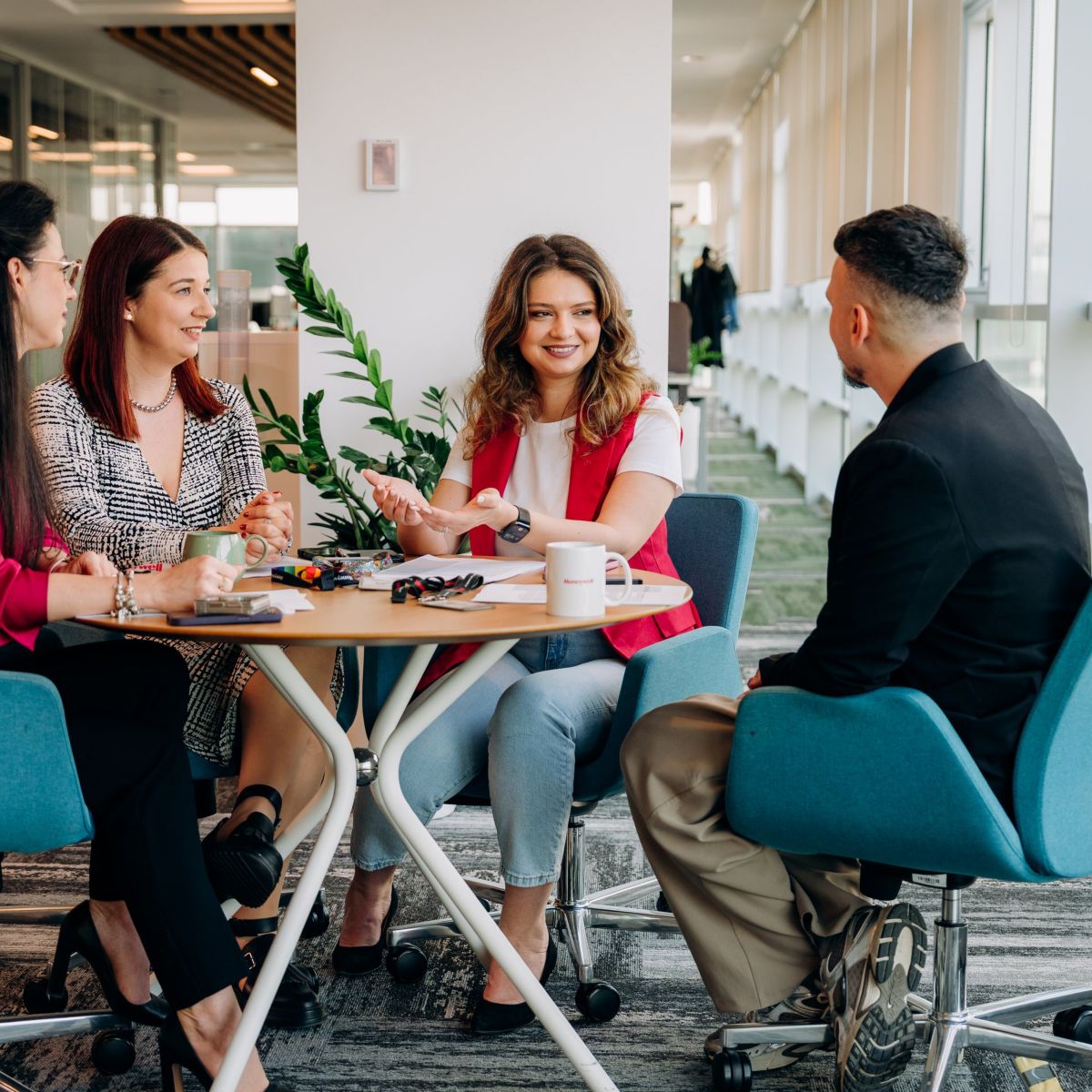 A diverse group of four professionals collaborates during a productive strategy session in a modern, sunlit office environment.