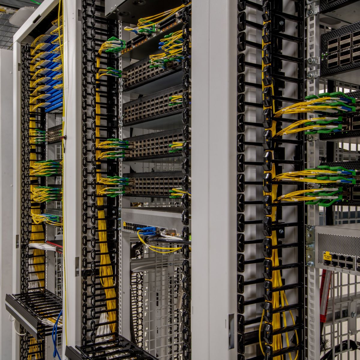 A row of organized network server cabinets featuring structured fiber optic cabling and high-density hardware in a secure facility.