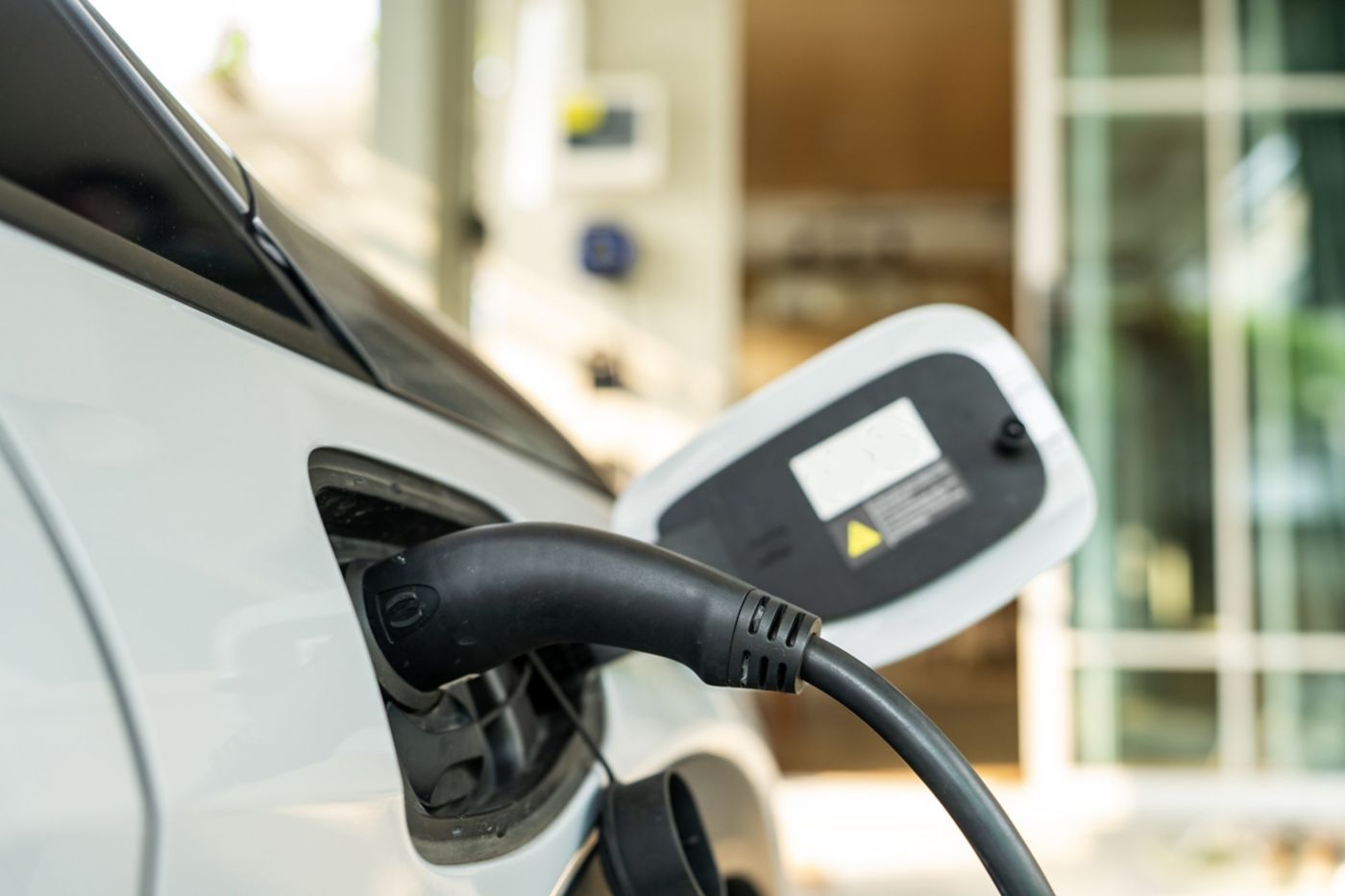 Close-up of a power cable connected to a white electric car at a home charging station.