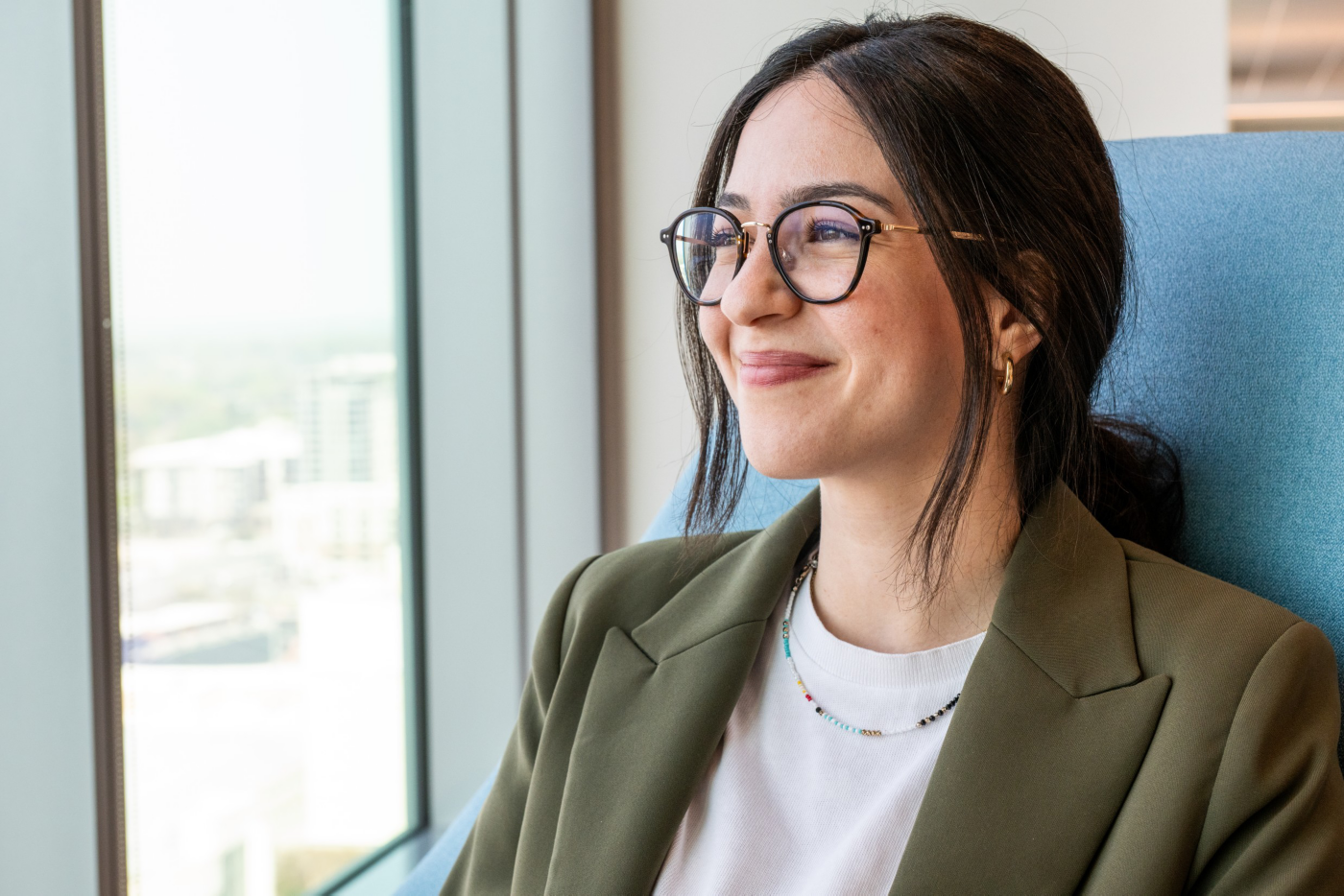 Employee smiling in a modern office setting, reflecting confidence, professionalism, and a positive workplace environment. 