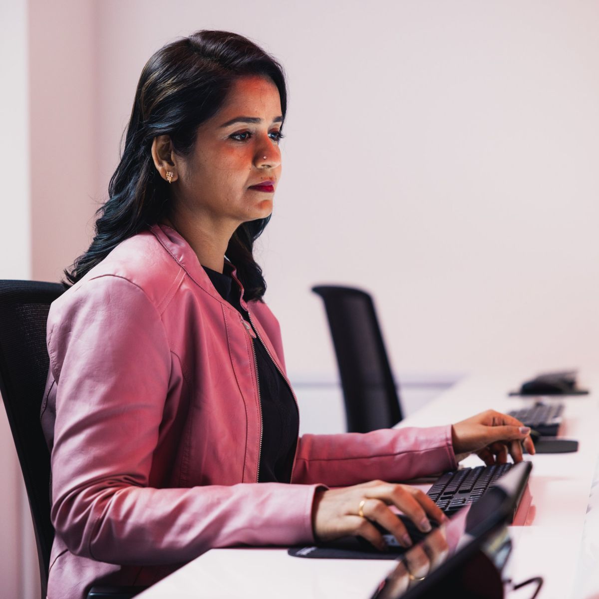 A focused professional working at a control room console, managing digital data across multiple monitors in a modern corporate office environment.