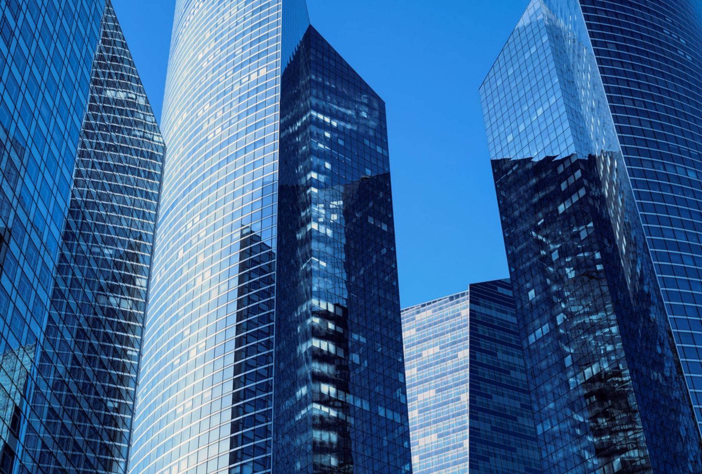 A close-up view of modern skyscrapers featuring reflective glass facades against a clear blue sky.