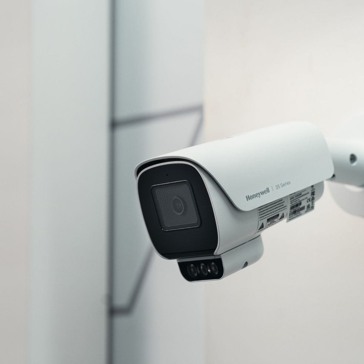 A professional-grade Honeywell 35 Series bullet surveillance camera mounted on a clean white wall for industrial monitoring.