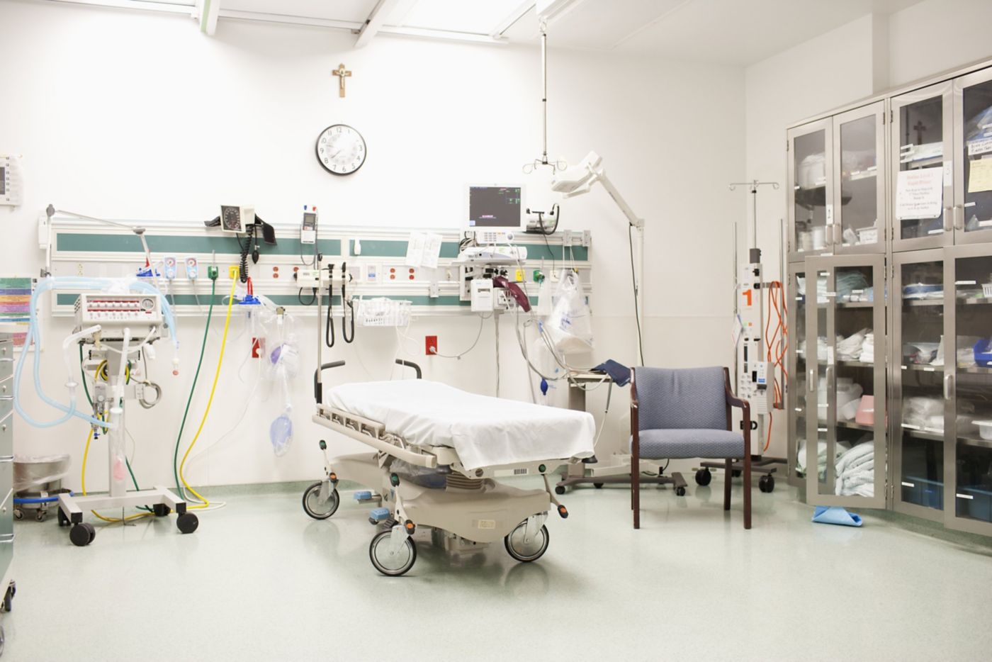 A clean, well-equipped hospital emergency room featuring a medical bed, monitoring equipment, and organized supply cabinets for critical patient care.