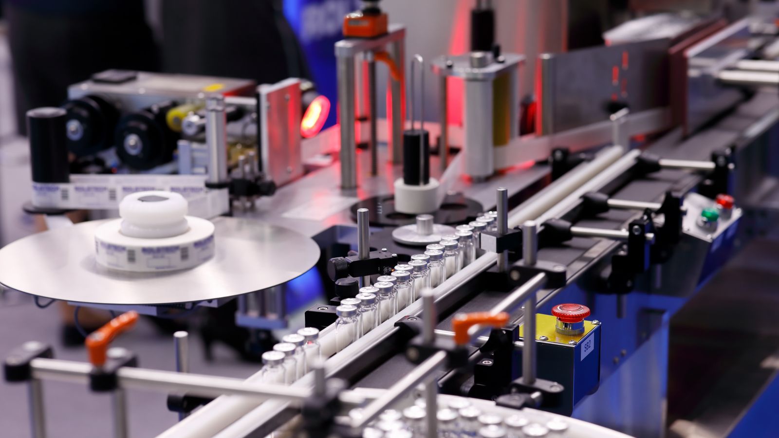 Automatic self-adhesive labeling machine for medicine bottles for injection. Selective focus.
