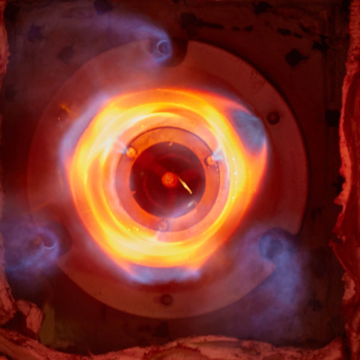 Close-up of a radiant industrial burner with glowing combustion core, highlighting controlled heat transfer, thermal efficiency, and high-temperature processing.