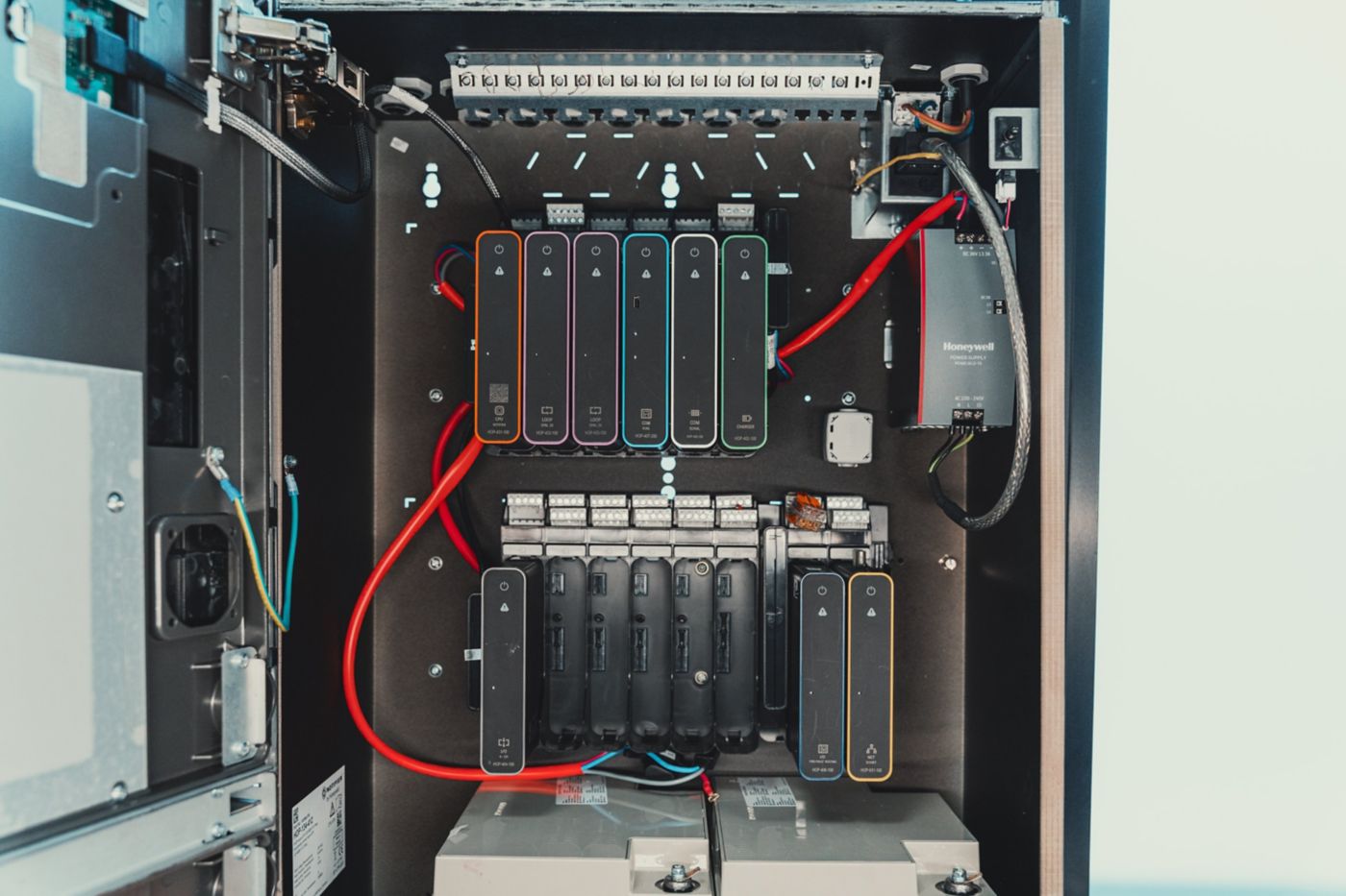 A view of an open industrial control cabinet featuring modular fire alarm system components and organized wiring.