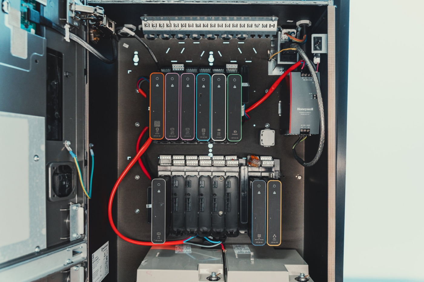 A view of an open industrial control cabinet featuring modular fire alarm system components and organized wiring.
