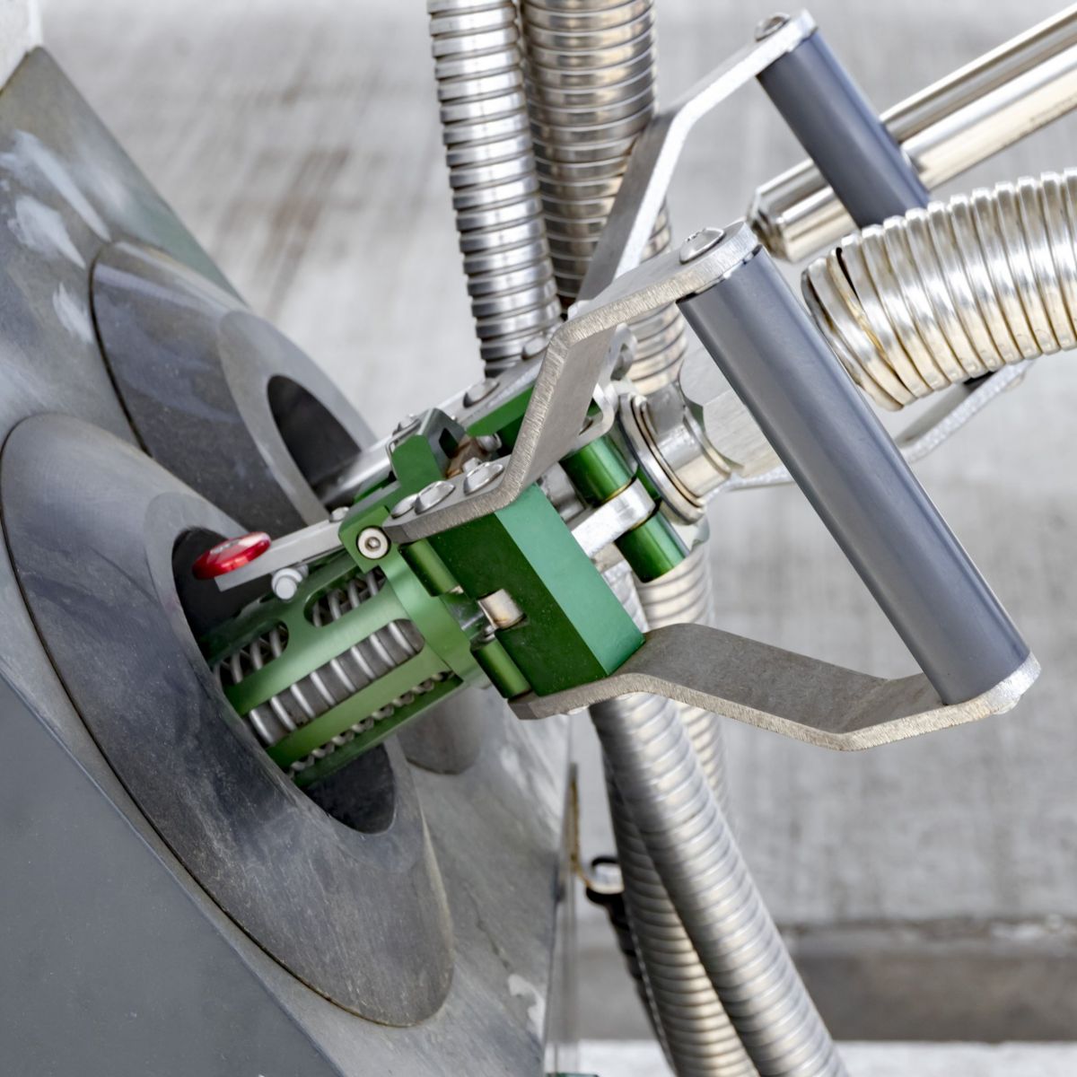 A close-up view of a specialized hydrogen fueling nozzle attached to a pump, highlighting the metal hoses and industrial mechanical design.