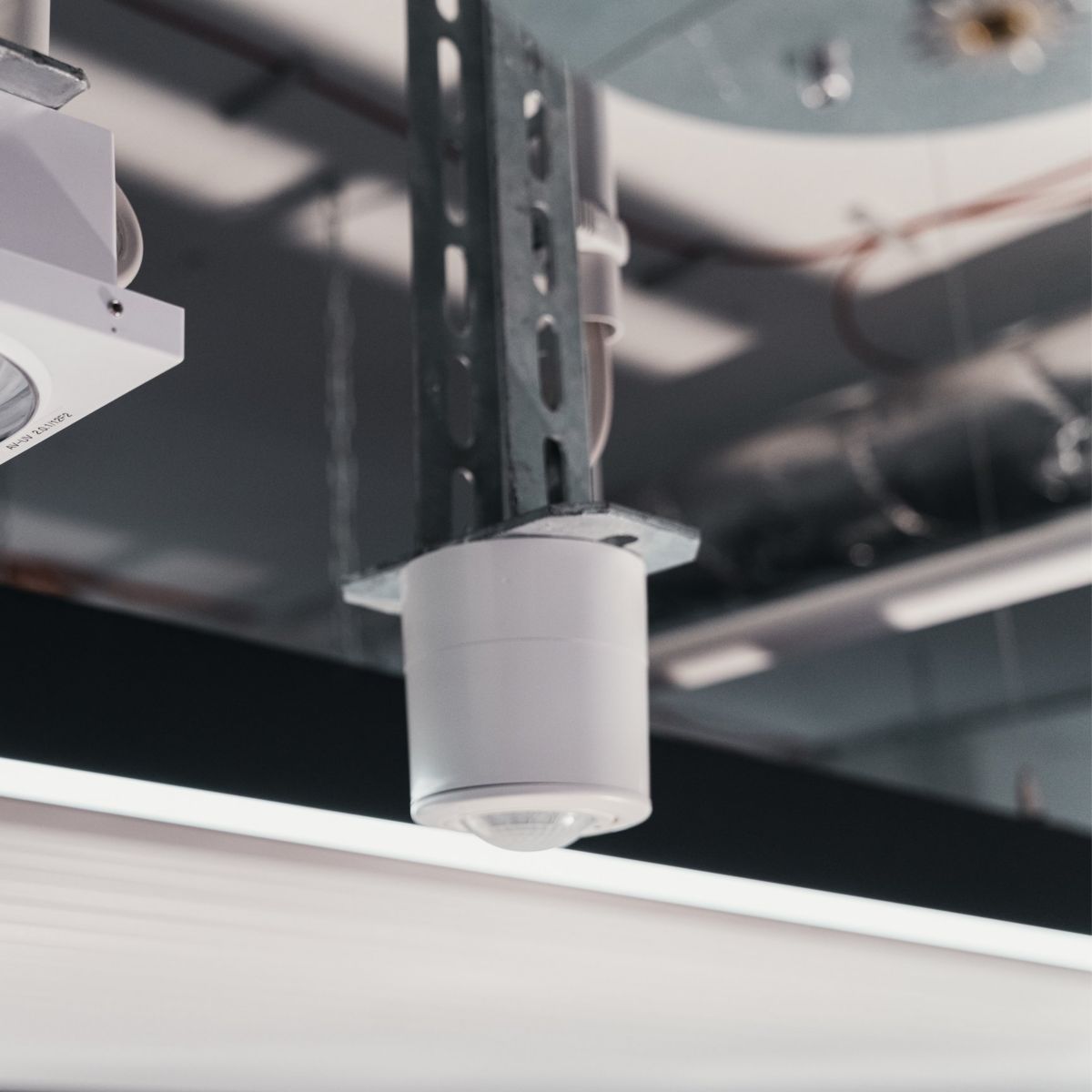 Modern ceiling-mounted LED spotlight and sensor system installed in an industrial facility.