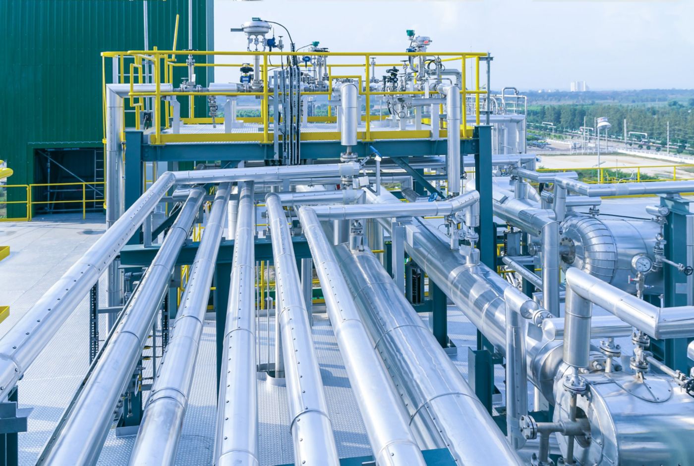 A complex network of stainless steel pipes and valves forms the modern processing equipment at an industrial refinery site.