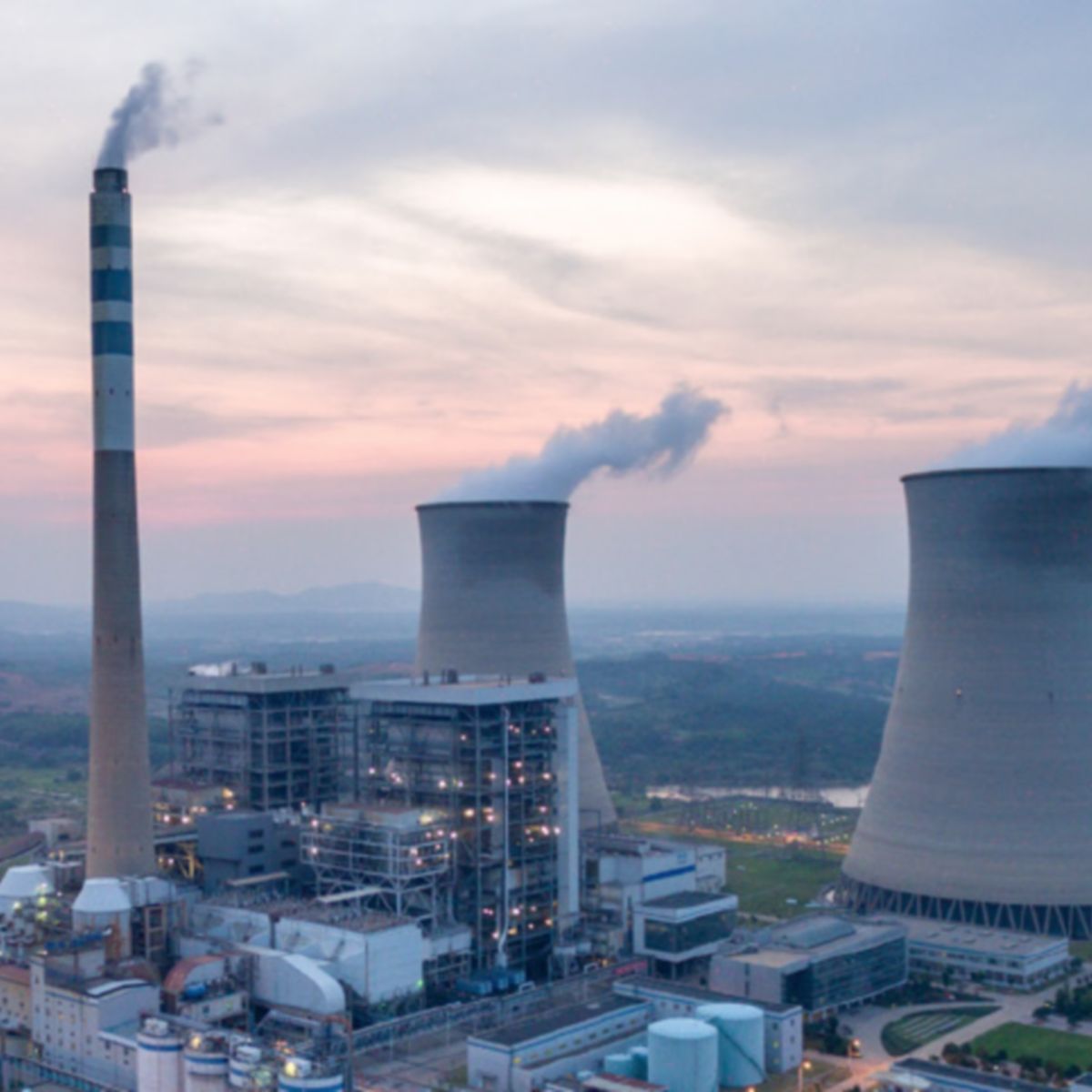 Large-scale power plant with cooling towers and emissions stacks, highlighting combustion control systems, fuel efficiency, and optimized energy production.