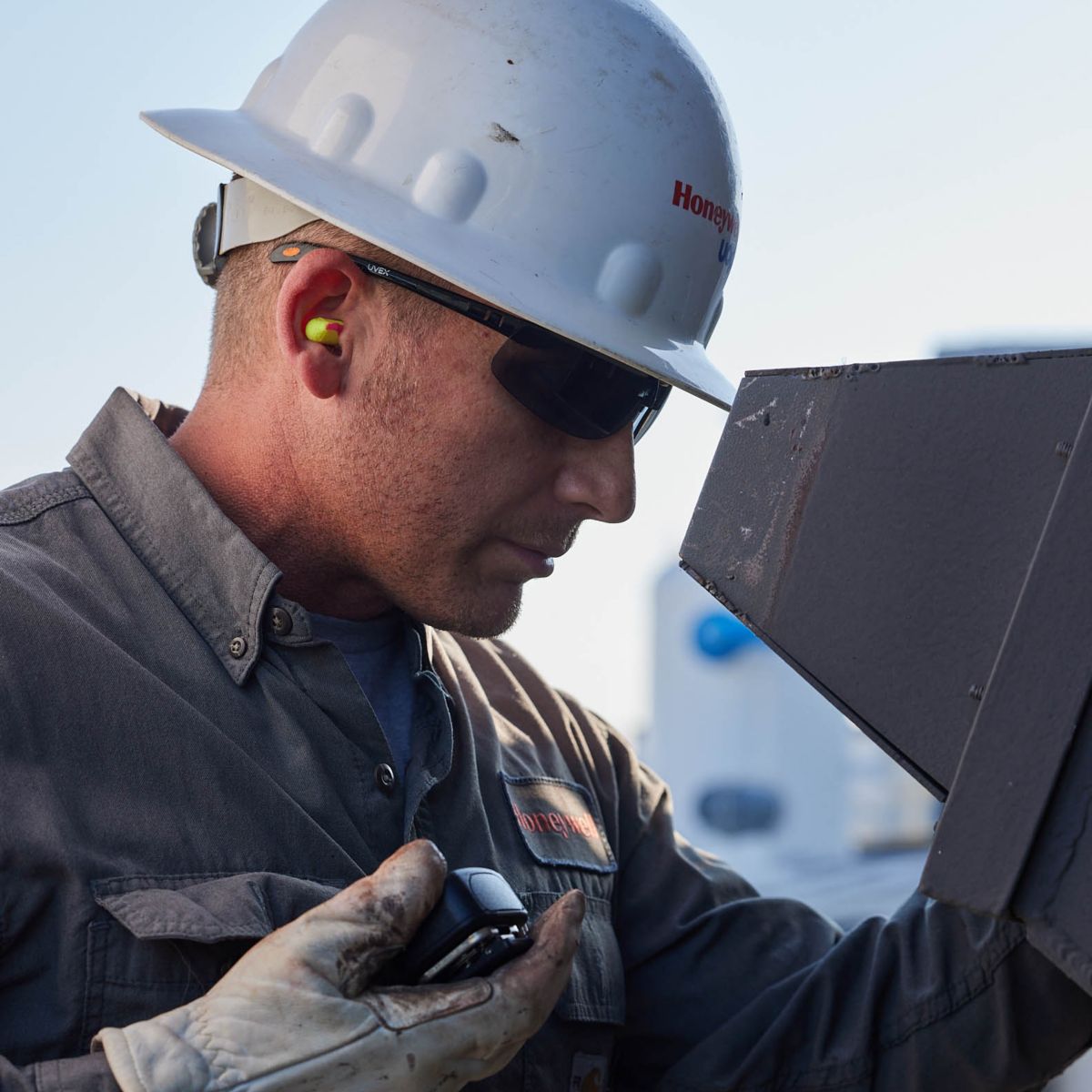 Technician wearing protective equipment inspecting industrial machinery, supporting safe operations, maintenance, and reliable system performance in demanding environments.