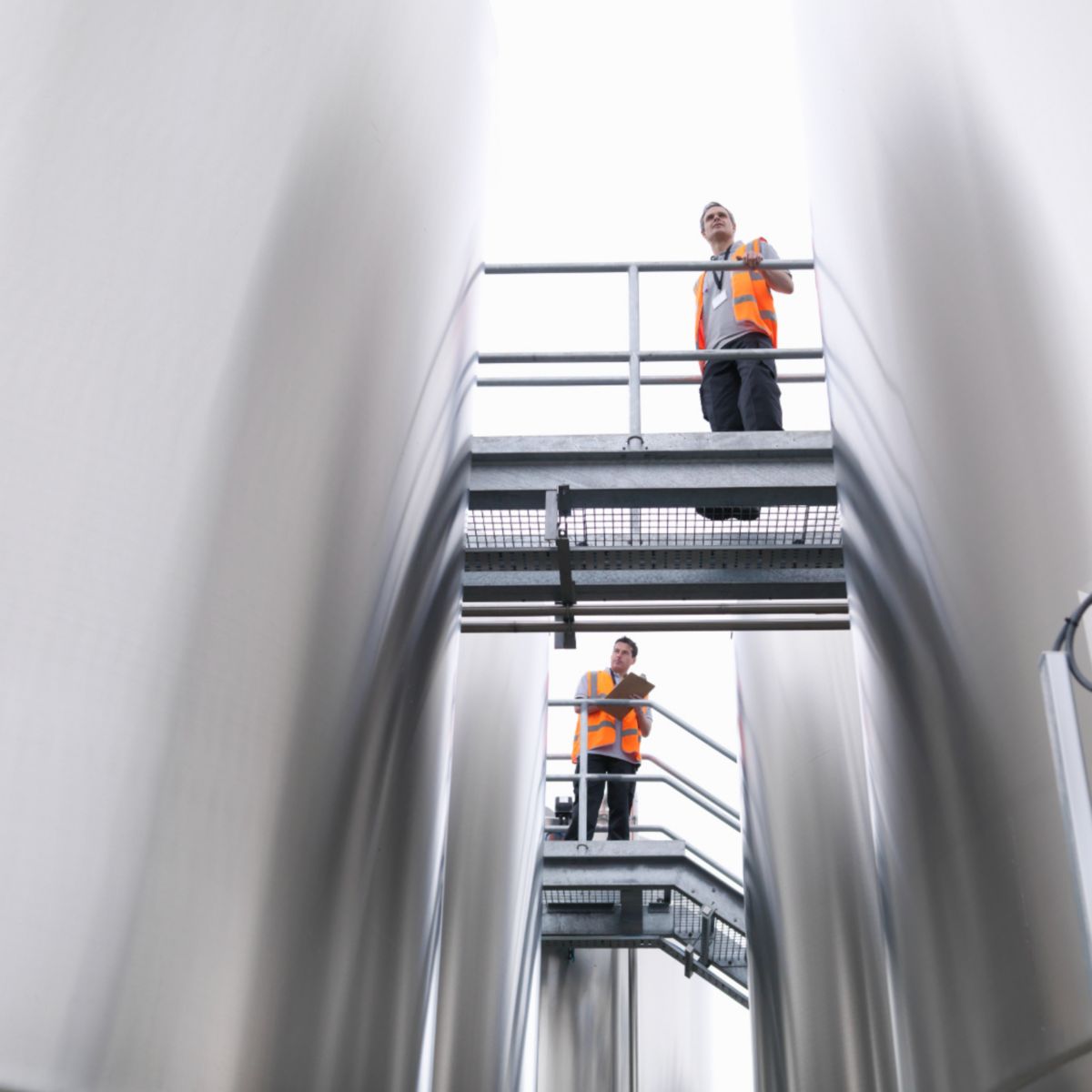 Technicians inspecting large industrial storage tanks and thermal systems, ensuring operational efficiency, safety, and reliable performance in process environments