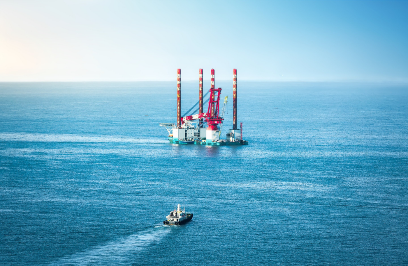 A large jack-up vessel operating in open water with a supply boat approaching.