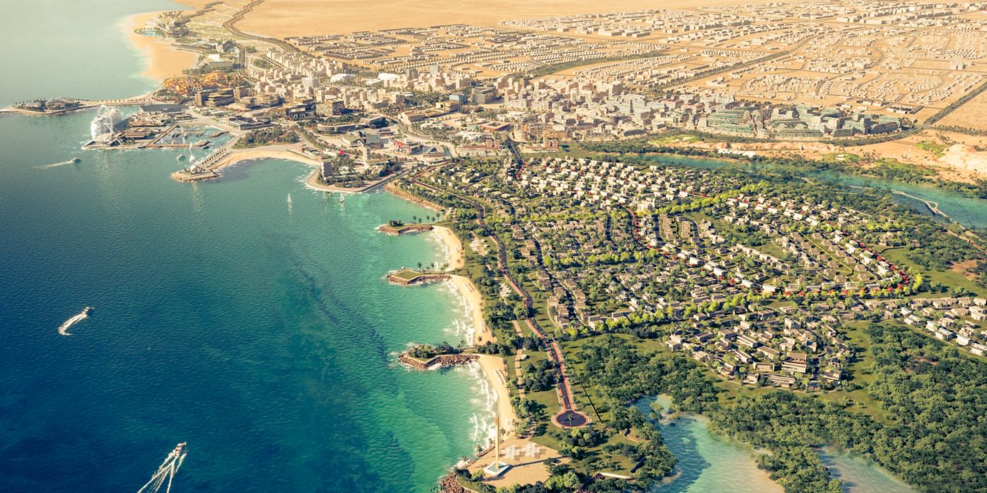 Aerial view of a coastal urban development showing residential areas, infrastructure, and shoreline with planned city layout.
