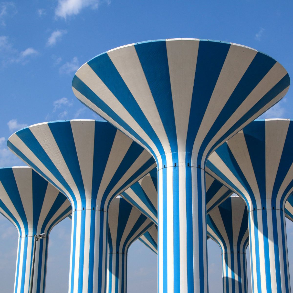 Architectural low-angle view of iconic blue and white striped mushroom-shaped water towers against a clear blue sky.