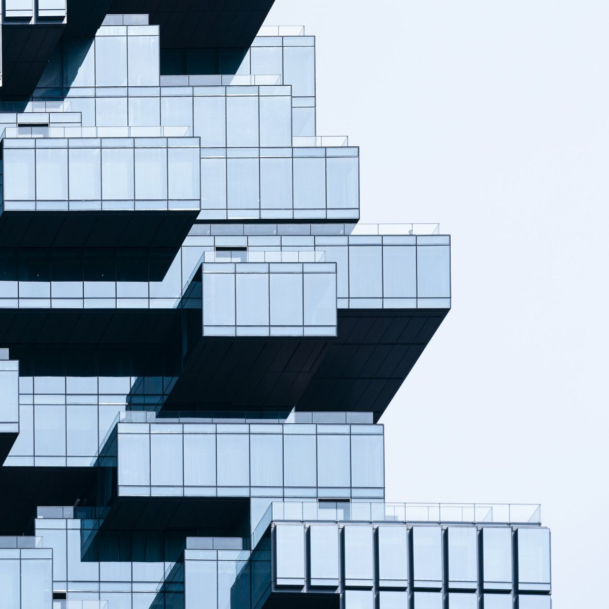 A minimalist architectural detail featuring modular glass building sections against a clean, bright sky.