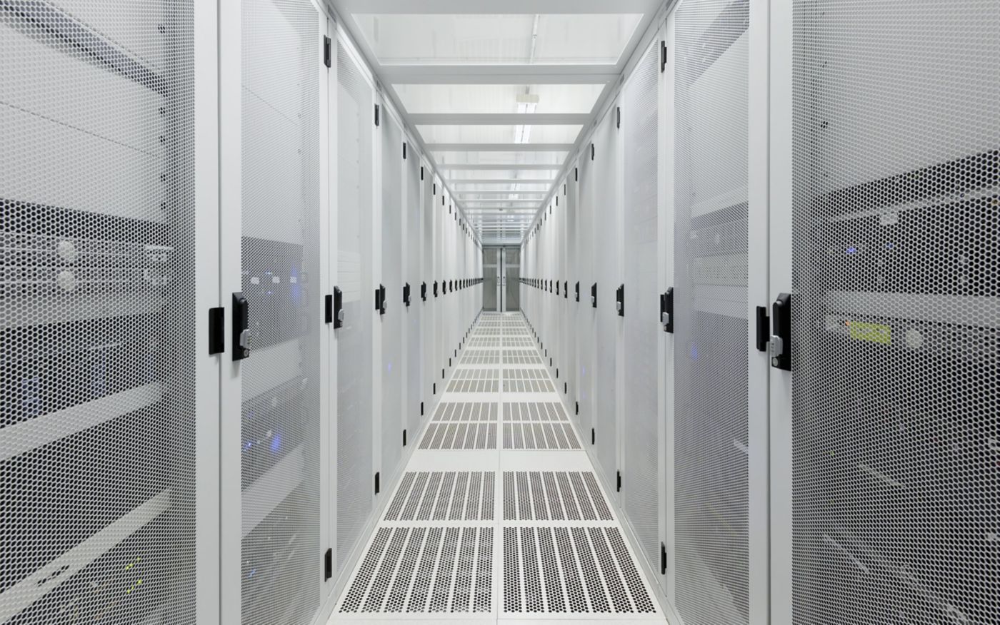 A symmetrical view down a bright, white data center aisle featuring rows of high-security perforated metal server cabinets.