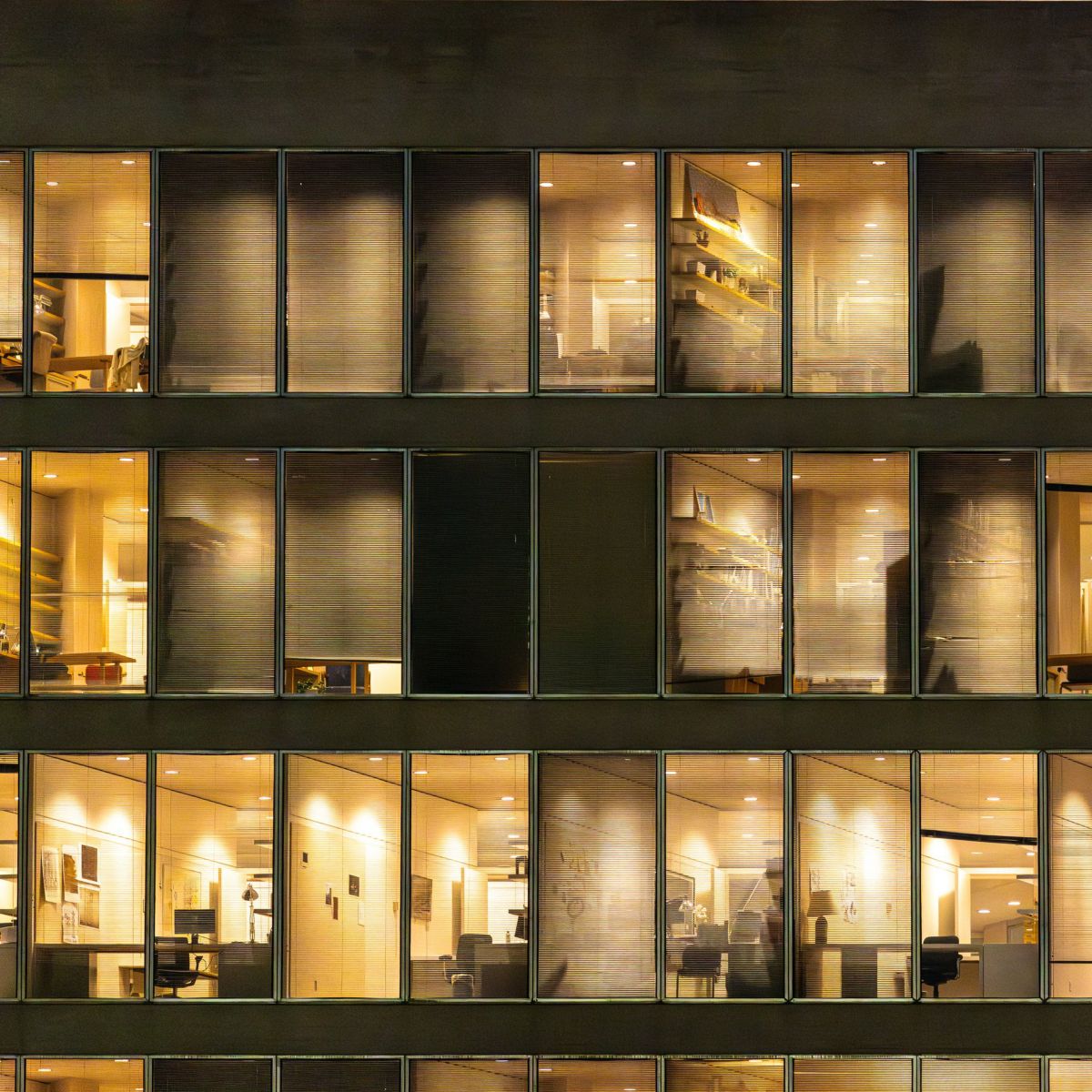 Illuminated office windows display a structured grid of workspaces during late-night hours.