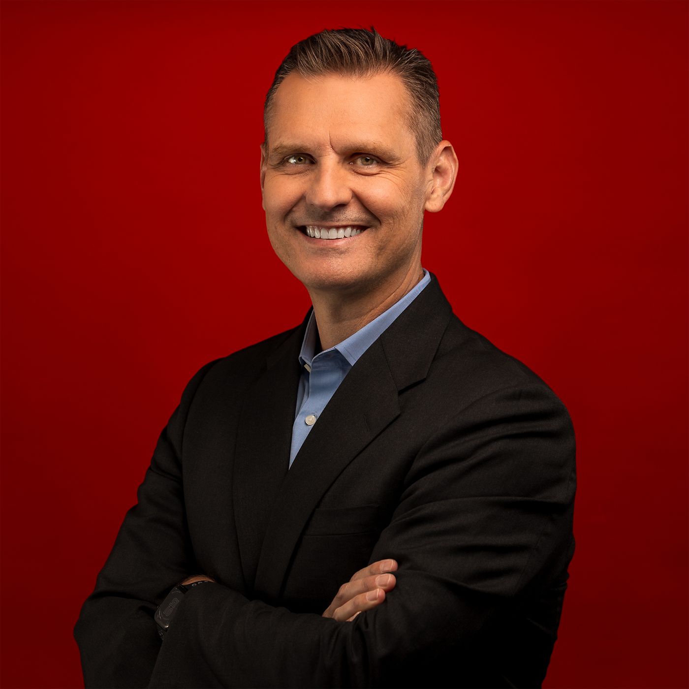 Professional portrait of Peter Kropik, captured against a bold red background.