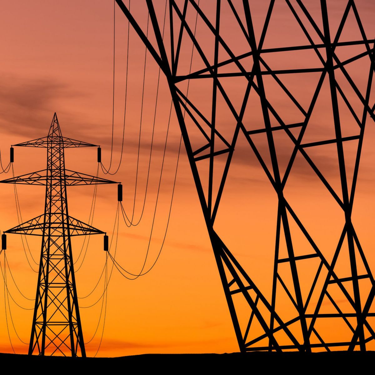 Silhouetted high-voltage electricity pylons frame a central tower against a vibrant orange sunset sky.