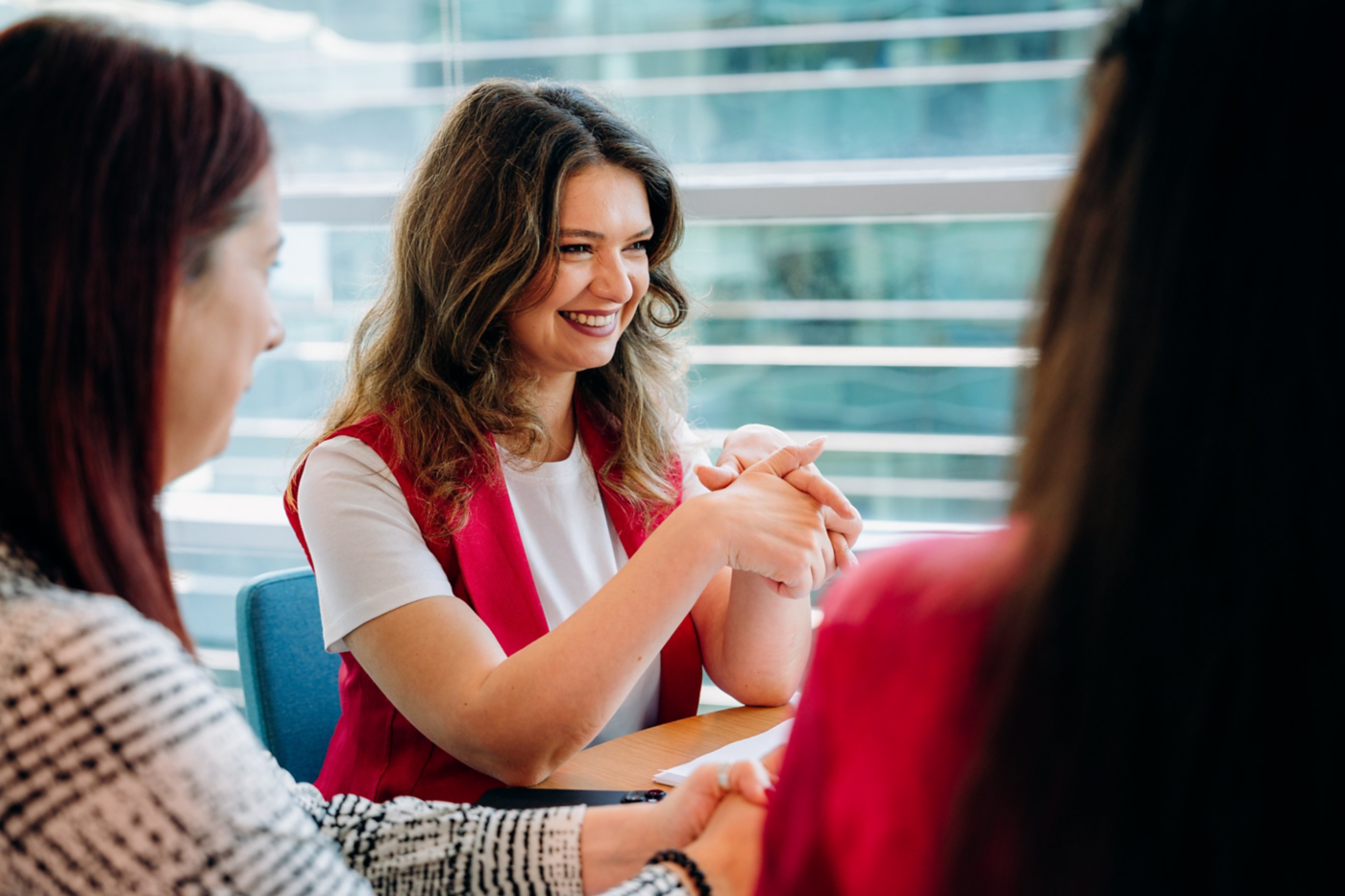 Three colleagues engage in a positive and collaborative discussion within a bright, modern corporate office environment.