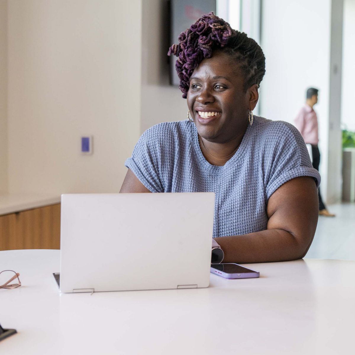 Individual working on a laptop in a bright modern office environment, showcasing productivity, focus, and flexible workspace design.