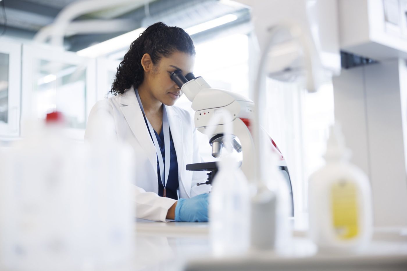 A focused scientist in a lab coat performs microscopic research in a modern laboratory setting.