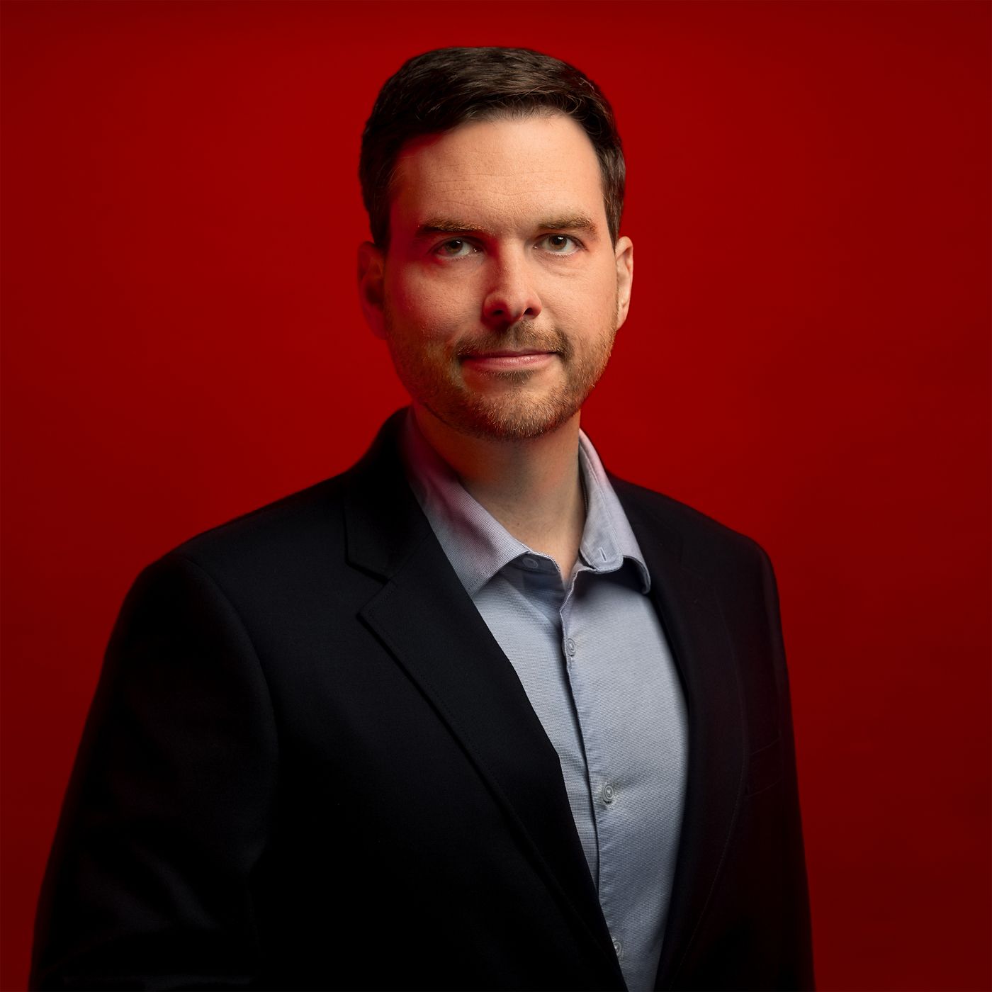 Professional portrait of Scott Hillpott, captured against a bold red background.