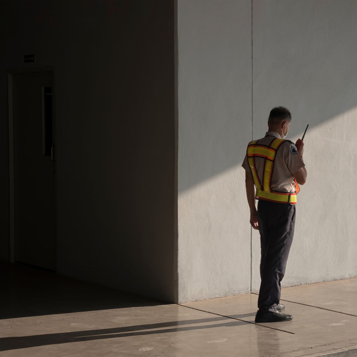 Professional image of a security guard using a walkie talkie inside a modern building to ensure safety and communication.
