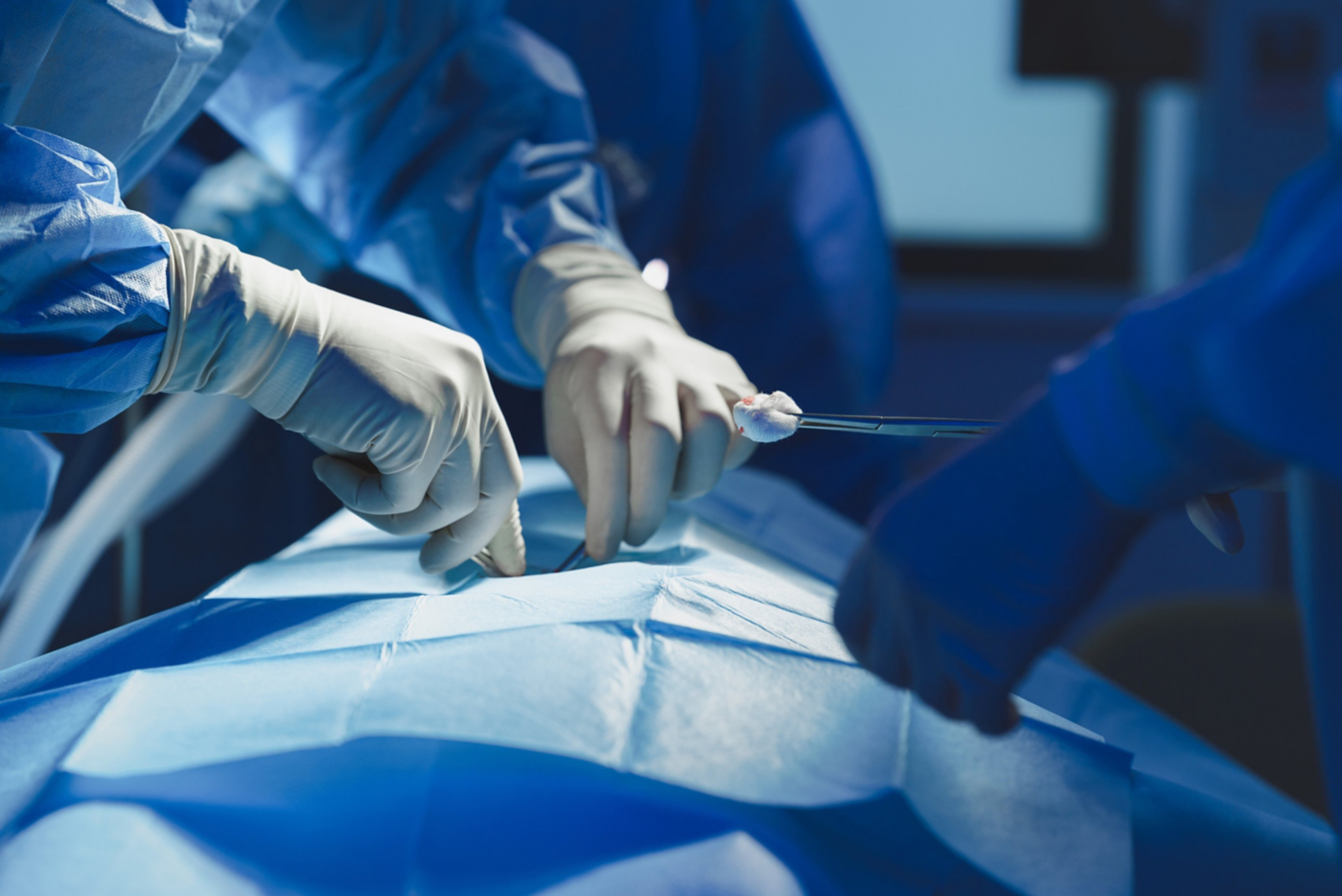 Medical professionals in sterile attire perform a precise operation under focused lights.
