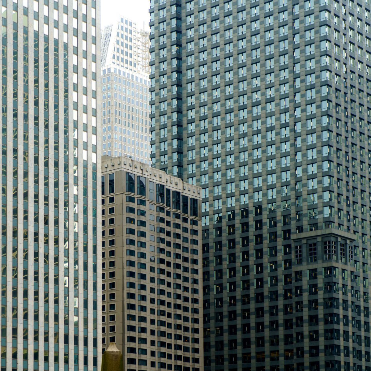 Abstract low-angle perspective captures the geometric patterns and contrasting glass facades of modern high-rise office buildings in a dense city center.