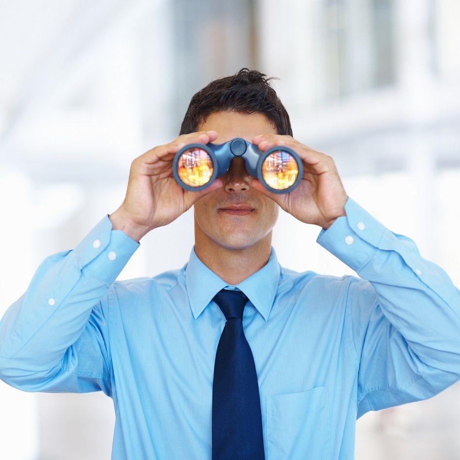 Portrait of young business man seeking through binoculars