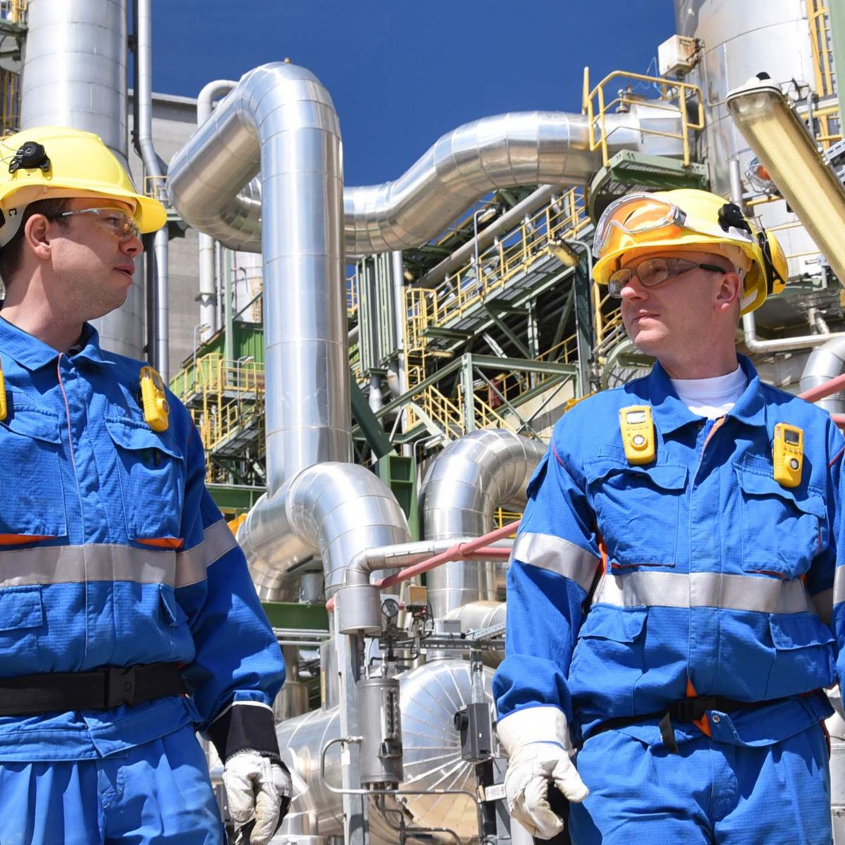 group of industrial workers in a refinery - oil processing equipment and machinery 
